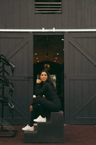 Woman sitting on steps inside a dark wooden barn