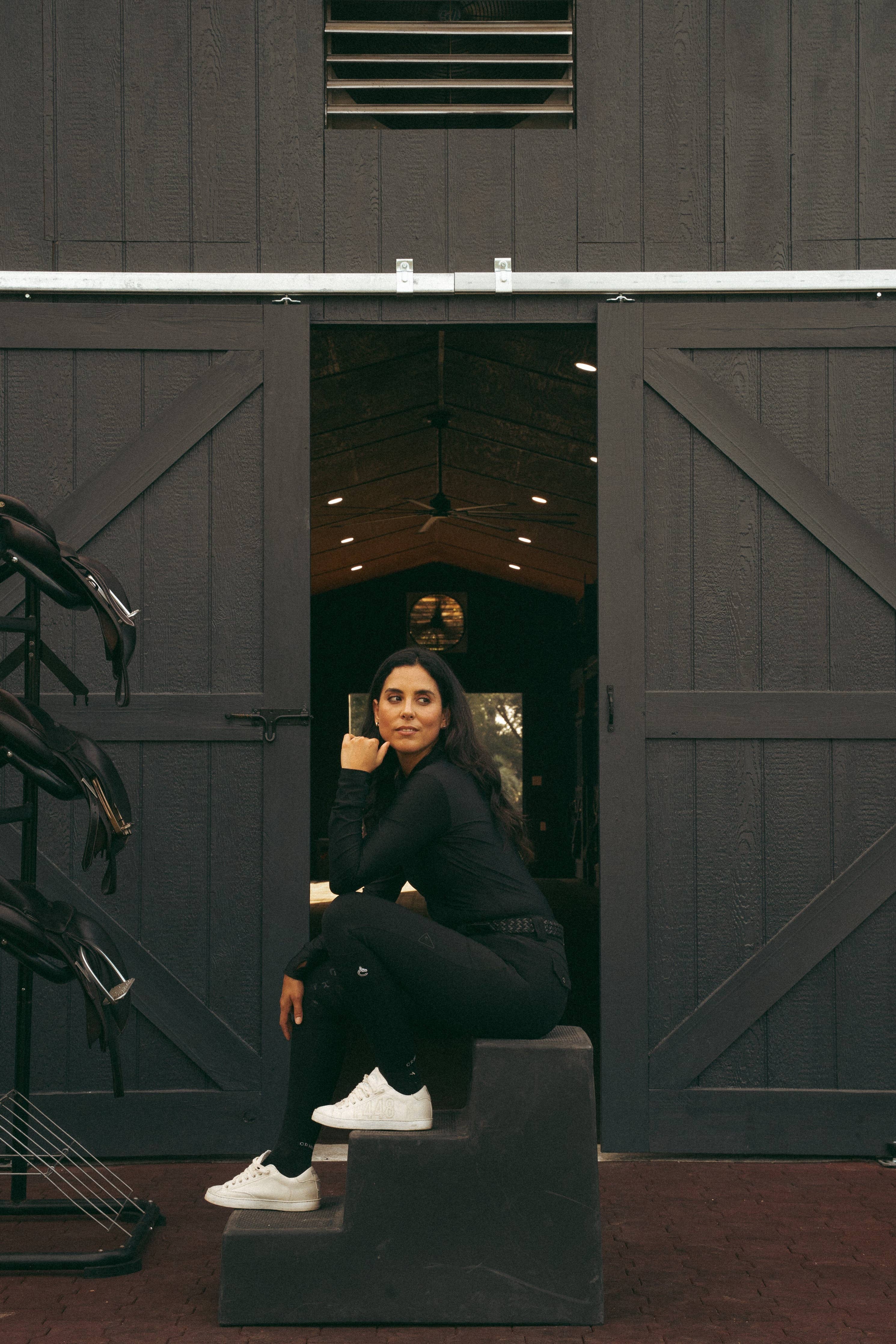 Woman sitting on steps inside a dark wooden barn