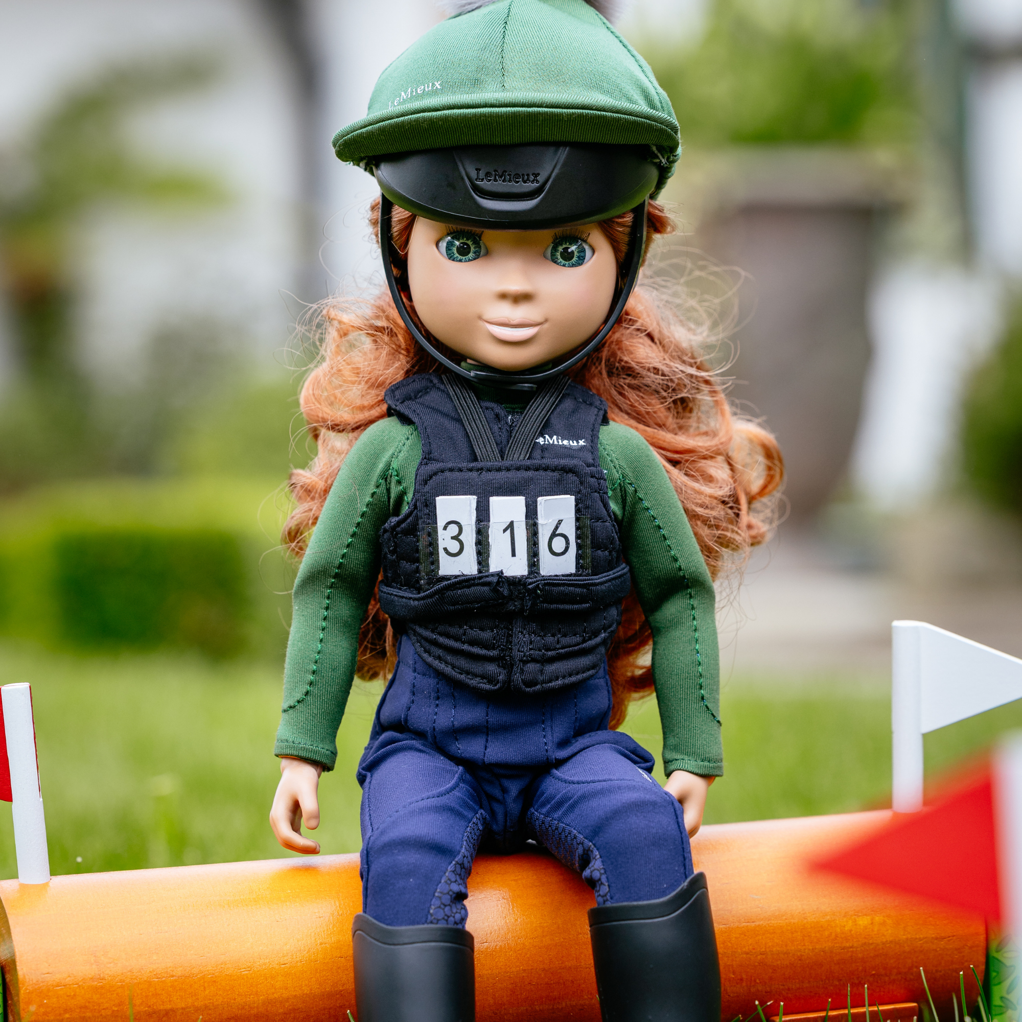 Doll in equestrian outfit with helmet sitting on an obstacle