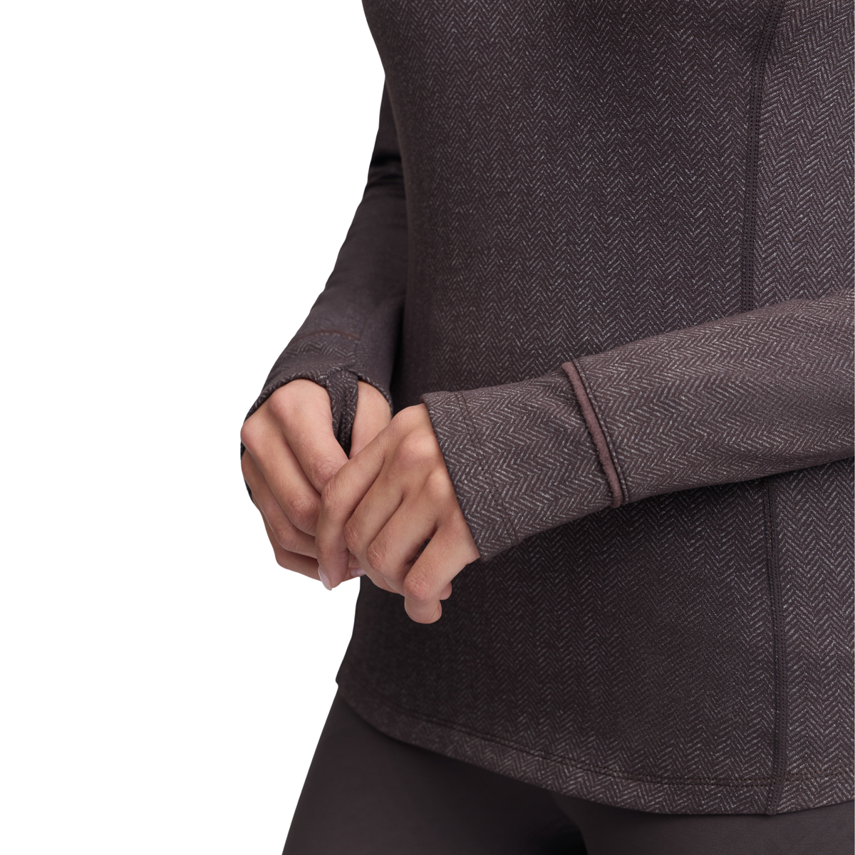 Close-up of a person wearing a dark brown herringbone-patterned long-sleeve athletic top, showing the hands and cuffs, against a plain white background.