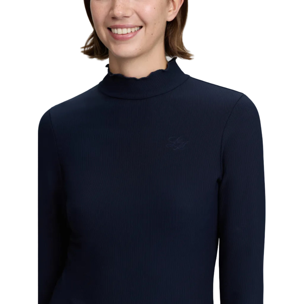 A close-up of a woman wearing a dark navy long-sleeve mock neck top with a subtle tonal embroidered logo on the left chest, set against a plain light gray background.