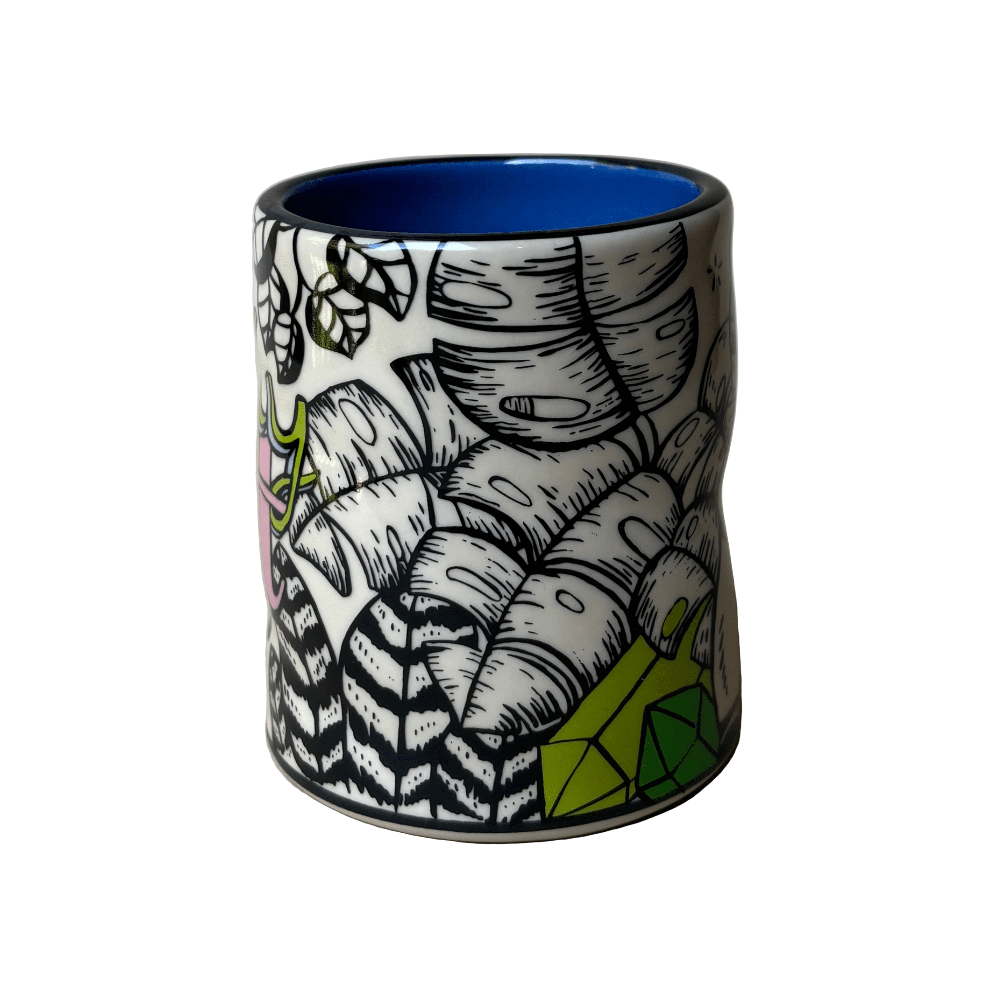 Ceramic tumbler with black and white leaf pattern and blue interior on a beige background