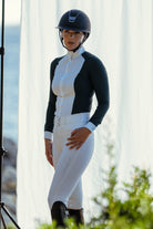 Person in equestrian attire standing outdoors with a blurred background