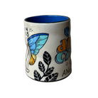 Ceramic mug with butterfly design and text on a plain background