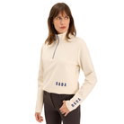 A woman modeling a cream-colored long-sleeve quarter-zip pullover sweatshirt with navy blue 'DADA' branding on the chest and sleeve, paired with dark brown pants against a solid white background.