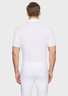 Man wearing a white polo shirt and white pants on a light gray background