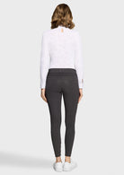 Woman wearing a white long-sleeve top and dark gray leggings on a white background