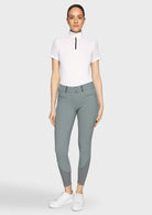 Woman wearing a white top and gray riding pants on a white background