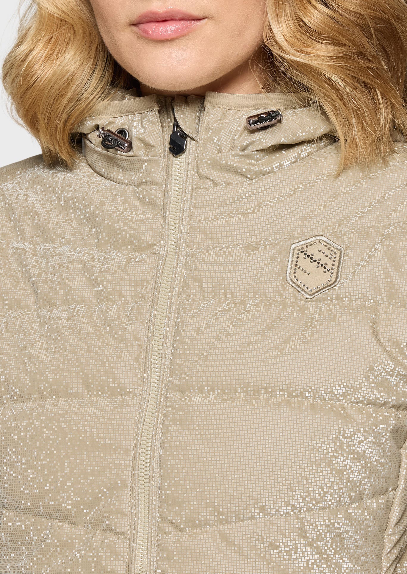 Close-up of a beige quilted jacket with a brand logo on a white background
