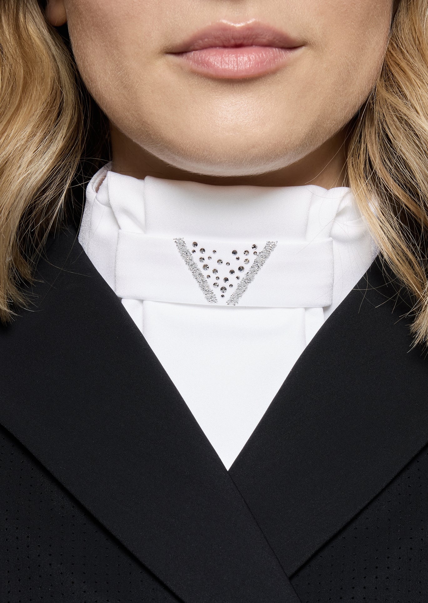 Close-up of a person wearing a black suit with a white shirt and decorative collar.