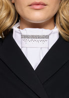 Close-up of a person wearing a black blazer and white shirt with a decorative collar.