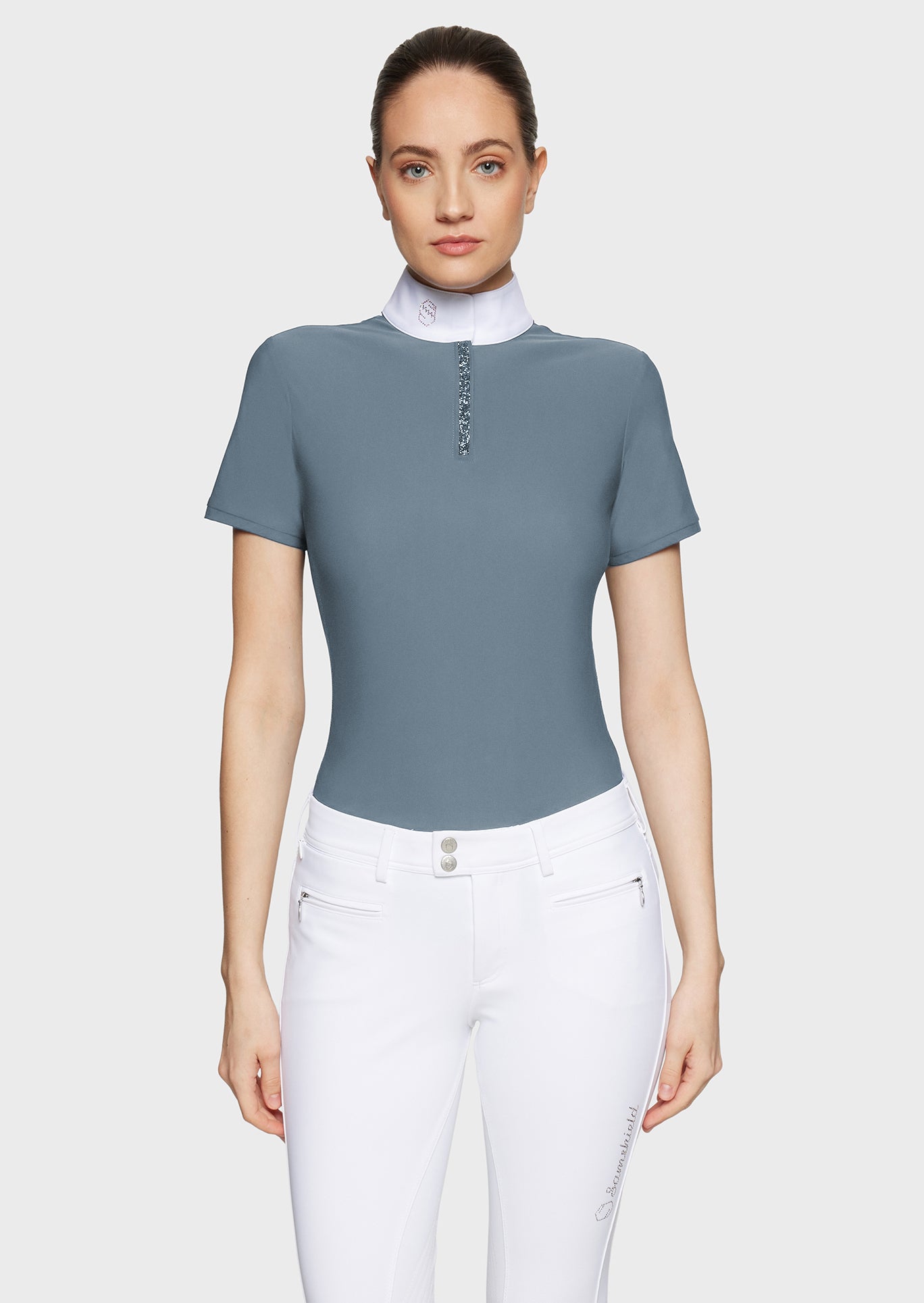 Woman wearing a gray short-sleeve top with a white collar and white pants on a light gray background