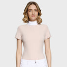 Woman wearing a beige short-sleeve top and white pants on a light background