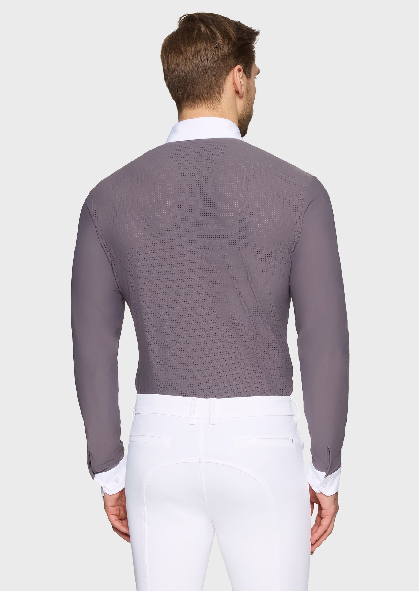 Man wearing a gray long-sleeve shirt over a white dress shirt with white pants on a light gray background