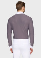 Man wearing a gray long-sleeve shirt over a white dress shirt with white pants on a light gray background