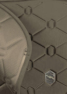 Close-up detail of a dark olive green protective pad or armor plate with a honeycomb pattern, featuring a small hexagonal metallic logo badge.