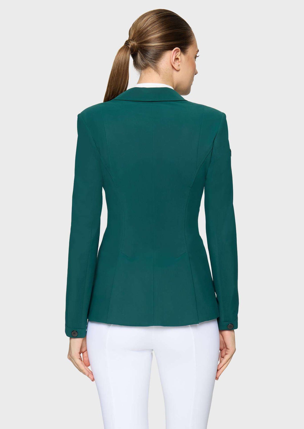 A woman shown from the back wearing a fitted dark teal green blazer and white pants against a light gray studio background.