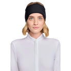A woman with blonde hair wearing a black athletic headband and a white high-neck top, photographed against a light gray studio background.