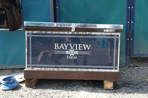 Bayview Farm trunk sitting on a wooden base outdoors.