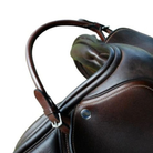 Close-up of a dark brown leather saddle with a curved handle and silver buckle, set against a plain white background.