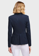 A woman shown from the back wearing a structured black blazer with a peplum waist and white pants, photographed against a plain white studio background.