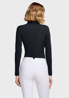 A woman shown from the back wearing a fitted black long-sleeve mock-neck top and white riding breeches against a plain white studio background.