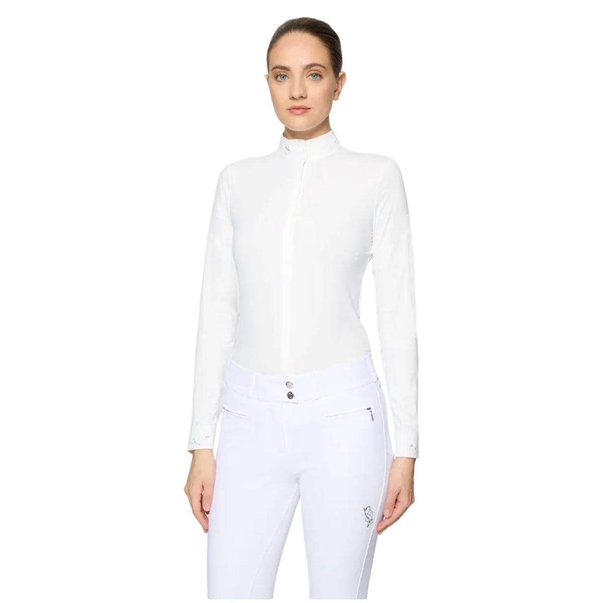 A woman modeling a white long-sleeve mock neck equestrian shirt and matching white riding pants against a light gray studio background.
