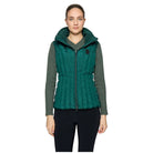 A woman modeling a dark green hooded puffer vest with ribbed knit sleeves, shown against a light gray studio background.