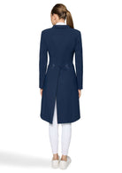 A woman viewed from the back wearing a navy blue long coat over a white collared shirt, white leggings, and white sneakers on a light gray studio background.