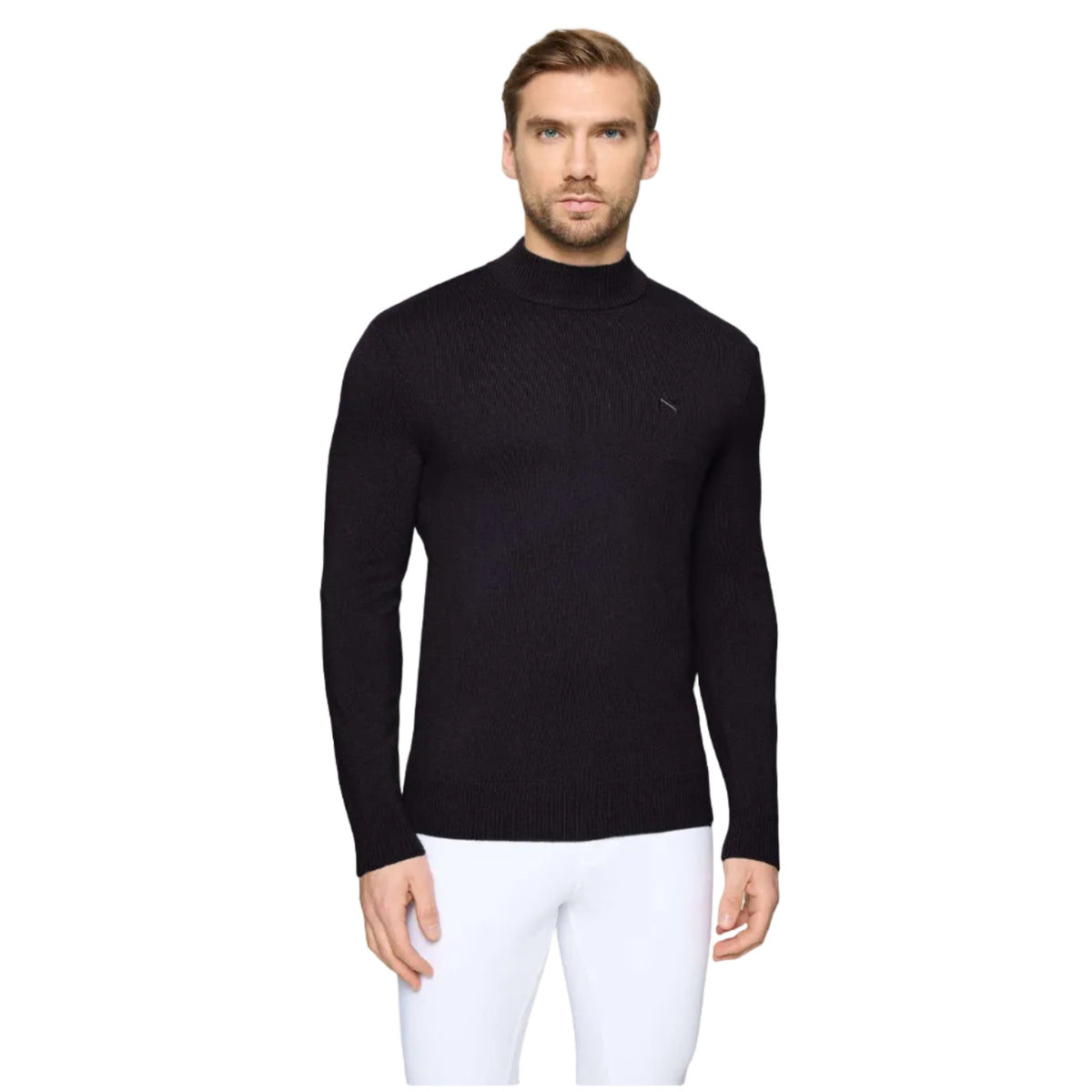 A man wearing a black long-sleeve mock neck sweater and white trousers, standing against a light gray studio background.
