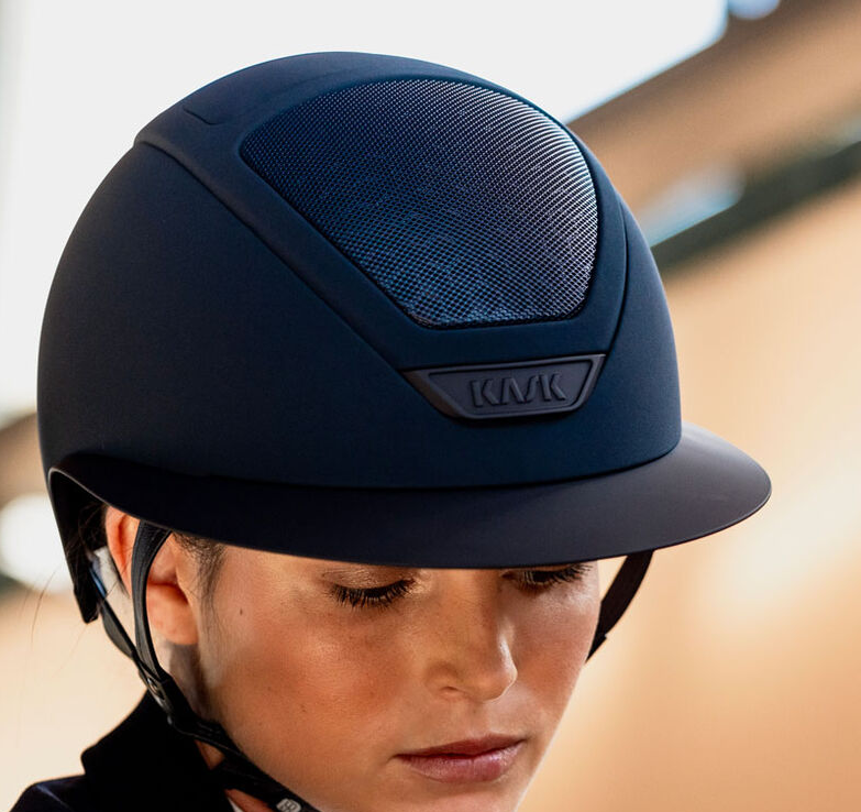 Person wearing a navy riding helmet with a blurred background
