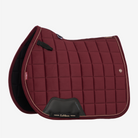 A LeMieux brand quilted navy blue equestrian saddle pad with gold piping and a black leather padlock at the front, displayed on a light gray background.
