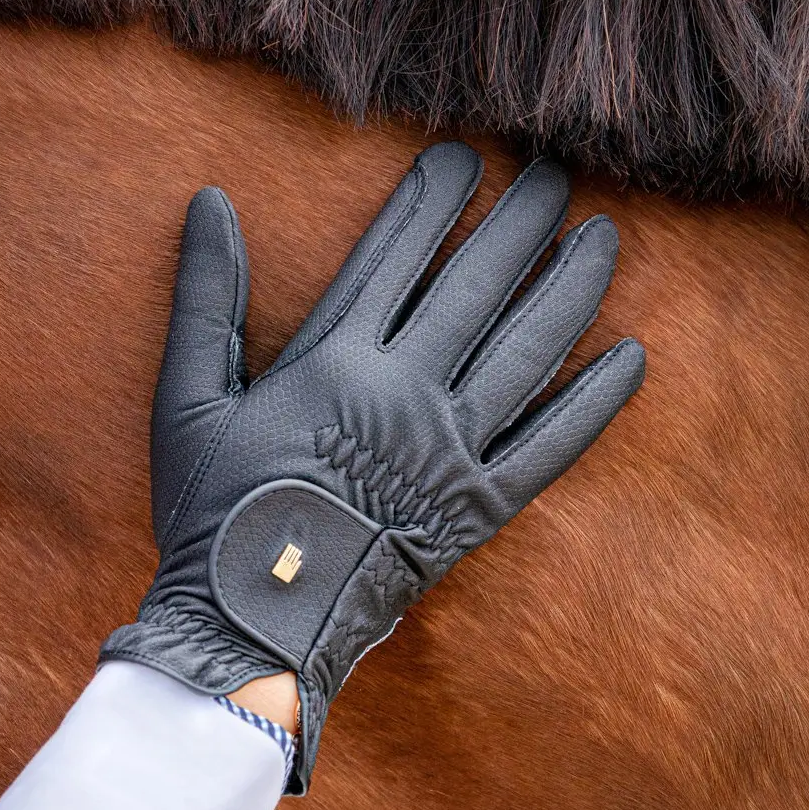 Gray equestrian glove being worn on a horse's back