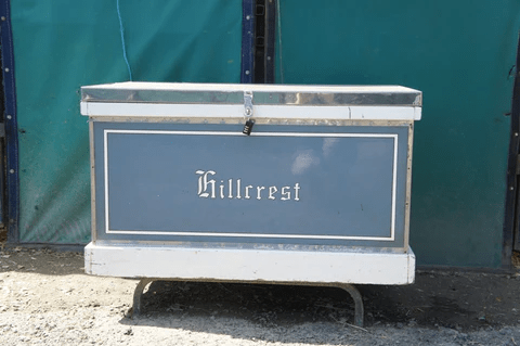 A blue equestrian tack box labeled 'Hillcrest' with a lock on the front.