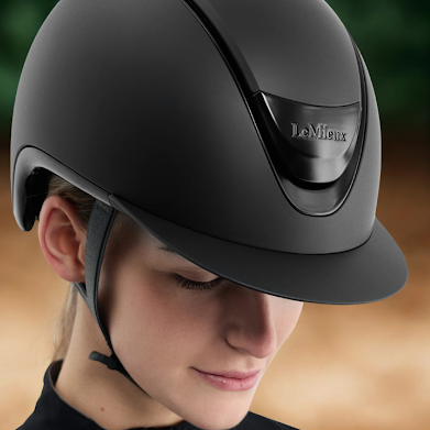 Person wearing a black riding helmet with 'LeMieux' branding against a blurred natural background