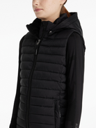 Person wearing a black puffer vest with a hood on a white background