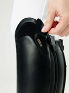 Close-up of a person adjusting a black shoe on a white background