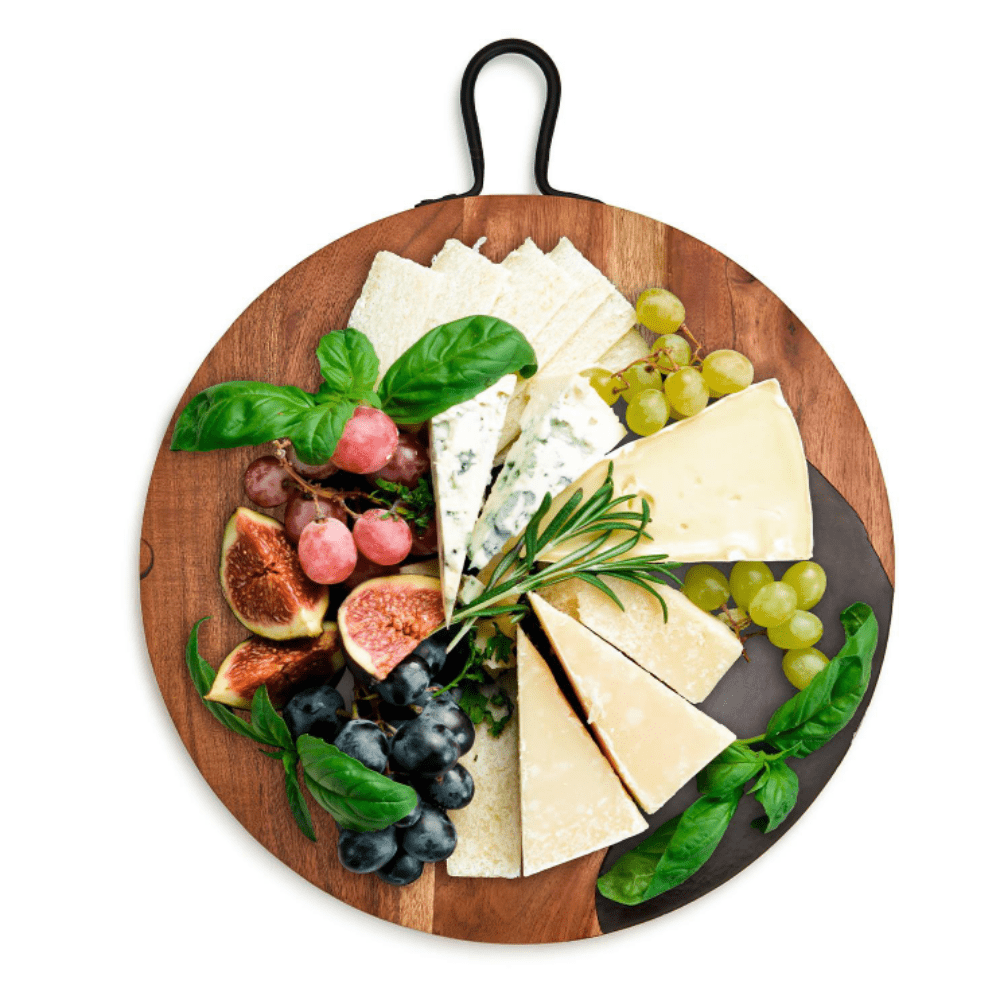 Round wooden serving board with a display of cheeses and fruit. 