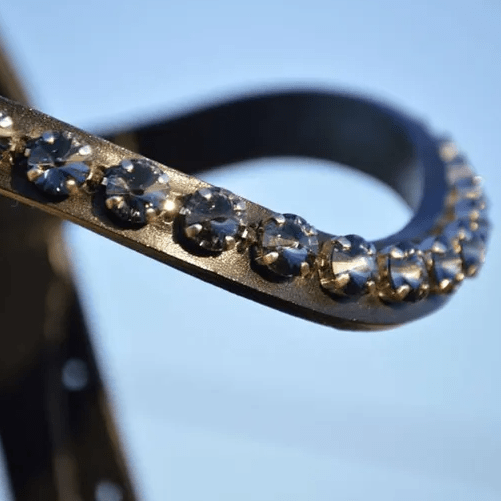 Close-up of a metallic object adorned with sparkling gemstones against a blurred blue background.