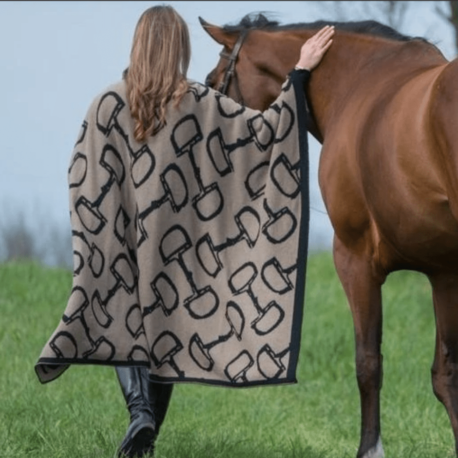 In2Green - Eco Bits Reversible Throw worn by a model leading a bay horse away from the camera through a grassy field. The throw is hemp with black snaffle bits and a black border.